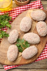 Uncooked meat patties, parsley, peppercorns and oil on wooden table, flat lay