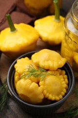 Fresh and pickled pattypan squashes with dill on wooden table, closeup