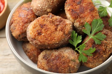 Tasty meat patties with parsley o wooden table, closeup