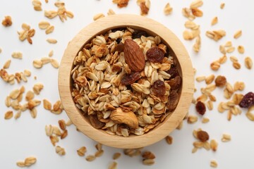 Tasty granola with nuts and raisins on white table, flat lay