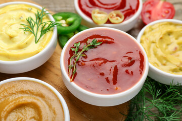 Different sauces and herbs on wooden table, closeup