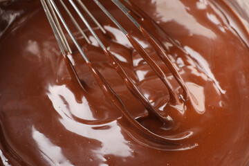 Melted chocolate and whisk in bowl, closeup