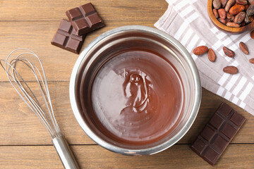 Melted chocolate, beans and pieces on wooden table, flat lay