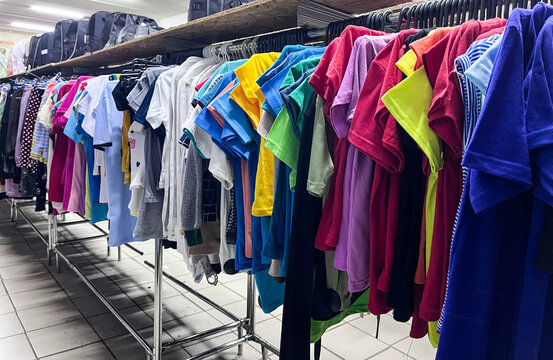 Clothes on hangers. The assortment of a cheap goods store. Colored T-shirts. Saving money in a crisis. Cheap shopping.