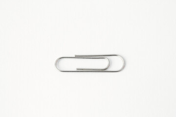 Single metal paperclip on a white background. A minimalist concept for business, connection, and office organization, with ample copy space.