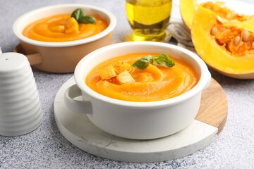 Delicious pumpkin cream soup with basil served on grey table, closeup