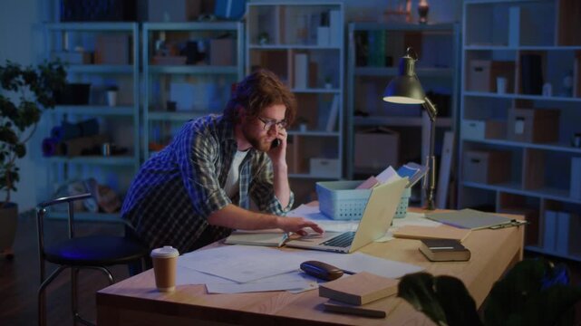 Focused Man Standing at Desk Late at Night, Working with Papers and Laptop. Concept of Paperwork, Research, Learning Process, Deadlines, and Balancing Study or Career with Productivity.