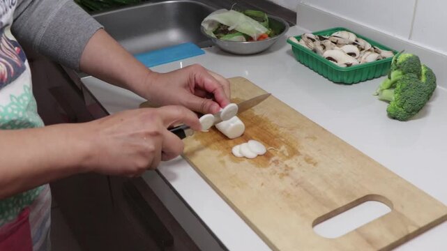Comenzar a picar ceboll&iacute;n en rodajas sobre una tabla de madera en la cocina