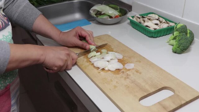 terminar de cortar en rodajas un ceboll&iacute;n en una tabla en la cocina