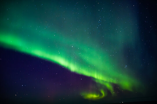 A mesmerizing display of the Northern Lights illuminates the night sky, creating a vibrant green and black tapestry of light