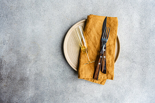 Overhead view of a rustic place setting with cutlery, a napkin and champagne flute