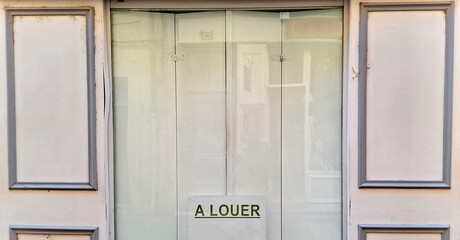 French vacancy sign in shop or store window reads a louer which translates as for rent