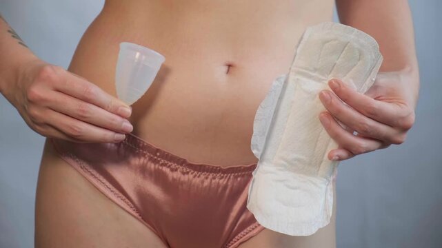 Close-up of female body with menstrual cup in hand. Feminine hygiene choice, woman health care routine and self-awareness. Daily care and the female cycle. Women health, menstruation or period