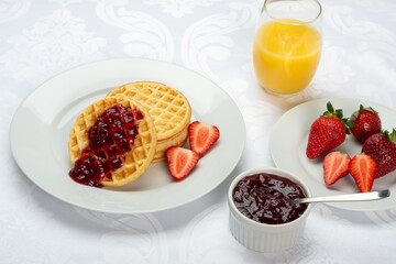 Delicious breakfast waffles with strawberry jam and orange juice
