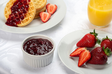 Delicious breakfast waffles with strawberry jam and orange juice