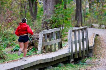 Jeune femme faisant du jogging sur un chemin en bois dans le parc en automne