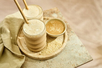 Sesame Tahini Latte Delight. Creamy sesame paste and iced tahini lattes on rustic travertine surface.