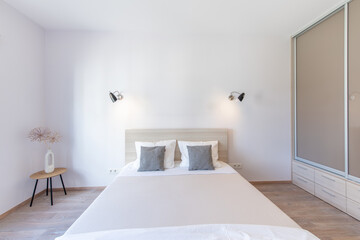 Wide Angle of Bedroom Interiom. King Size Double Bed and Wardrobe in Background. White Walls. Family Home