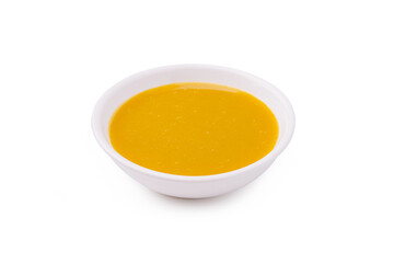 Golden sauce in a small white bowl on a clean surface showcases vibrant color