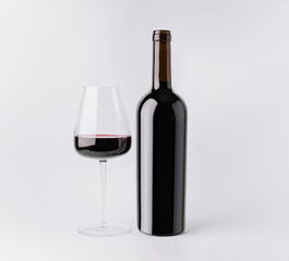 Enjoying red wine in a glass beside a bottle on a white background