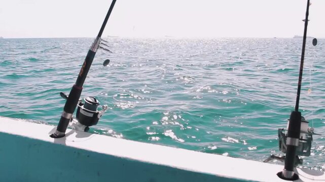 Two fishing rods on a boat with bright glittering sea