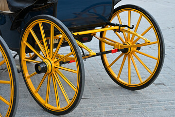 Close-up view of a traditional horse carriage wheel in Seville, featuring bright yellow spokes and...