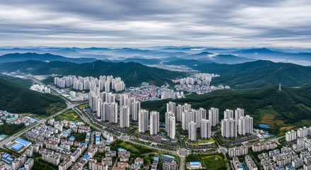 Cityscape skyscrapers overlooking green mountains under dramatic sky