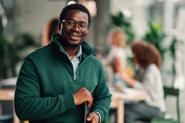 African american businessman smiling holding laptop in office