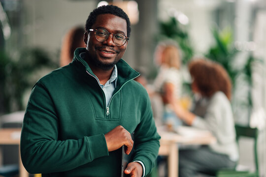 African american businessman smiling holding laptop in office