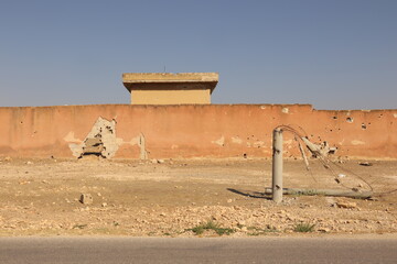 A shattered electricity pole in Aleppo, Syria, scarred with bullet holes and explosion marks,...
