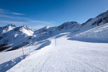 Snow-covered alpine ski resort slope with mountain backdrop