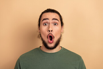 Young man with surprised expression wearing a green tshirt against a beige background perfect for casual lifestyle fashion and advertising campaigns