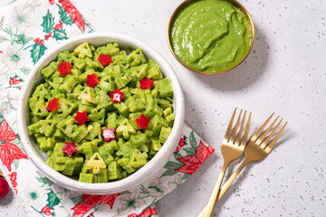 A bowl of green pasta with red stars and a green sauce