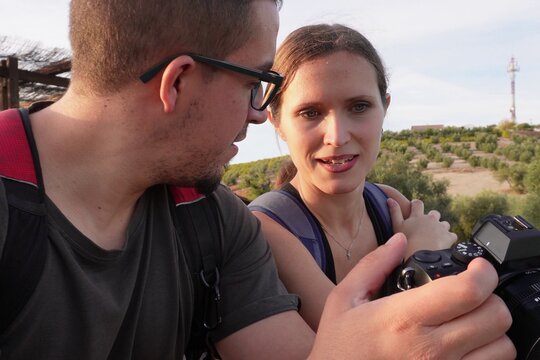 Close-up of a couple reviewing images on a digital camera after hiking, smiling and talking outdoors. Concept of photography, friendship, and exploration. - Powered by Adobe
