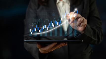 A business professional engages with financial data on a tablet, displaying dynamic graphs and growth indicators in a modern workspace, reflecting market analysis. Impute