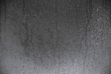 Detailed macro closeup of a dark, rugged rock surface with a wet, speckled texture, creating an abstract and modern natural background.