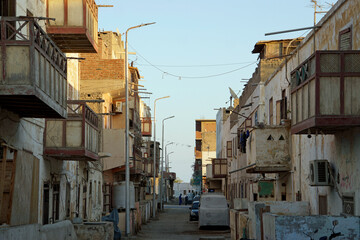Narrow, dirty dirt road between crumbling multi-story buildings