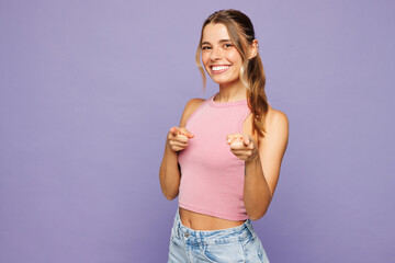 Young smiling happy woman wear pink tank top casual clothes point index finger camera on you motivating encourage isolated on plain pastel light purple background studio portrait. Lifestyle concept.