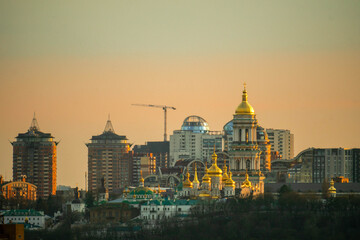 Obraz premium Golden domes of an Orthodox cathedral against modern city skyline at sunset