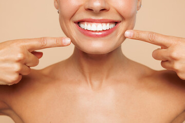 Beautiful half naked topless young woman 20s with nude make up point index fingers on opened mouth teeth isolated on beige background studio portrait. Skin care healthcare cosmetic procedures concept.