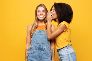 Two young friends buddies women wear denim casual clothes together whispering gossip and tells...