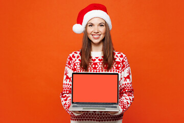 Merry smart young IT woman wear red Christmas sweater Santa hat posing hold use work on blank...