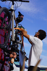 nomadic lifestyle. man placing his bicycle on the bike rack of his camper van