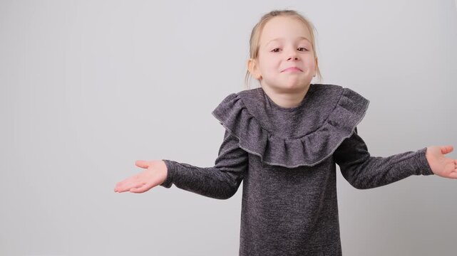 Confused little girl shrug as sign of doubt making choice Cute unsure little girl shrugging shoulders and outstretching hands. children emotion concept