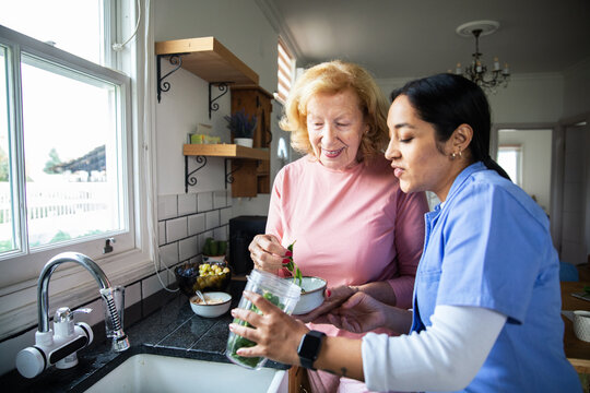 Senior woman cooking with caregiver in kitchen