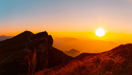 Obraz premium Alpine sunset or sundowner with hiker silhouettes and a summit cross at Mount Diedamskopf, Schoppernau, Bregenz, Vorarlberg, Austria