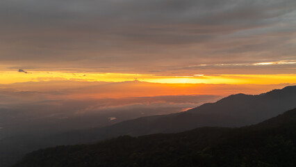 Golden sunrise light over mountain range with layers of fog and shadow, stunning nature view in Thailand, travel and adventure background.