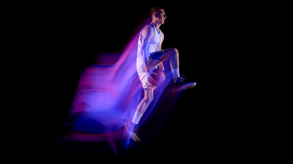 Basketball player in midair holding ball with vivid neon light trail on dark background. Concept of biomechanics, sports medicine, physiotherapy training, and human motion research © master1305