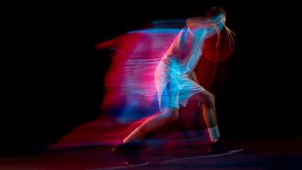 Basketball player pushing forward with ball creating red and blue motion streaks. Concept of sports marketing, energy flow, movement analysis, and fitness coordination.