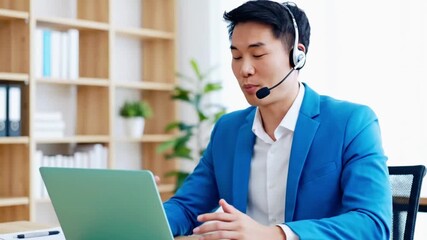 Asian businessman in headset using laptop during online meeting at office - Powered by Adobe